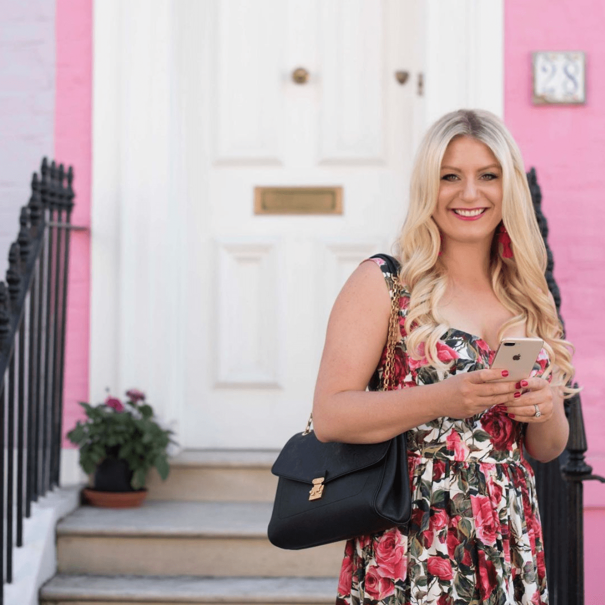 Emily Williams smiling holding her phone and wearing a floral dress