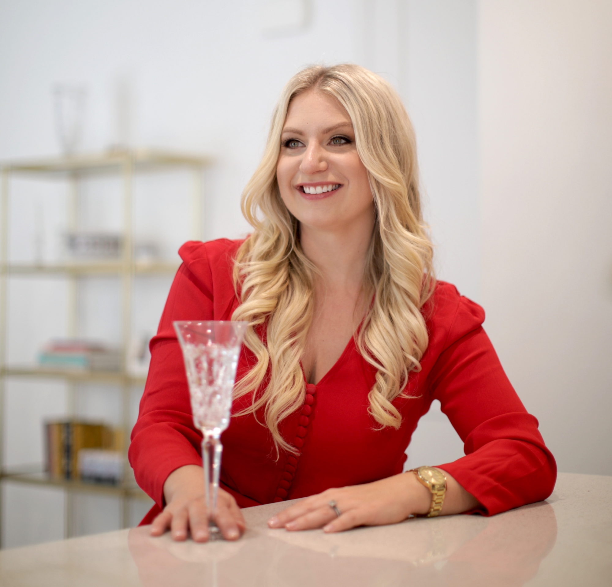 Emily Williams holding a champagne glass and wearing a red blazer