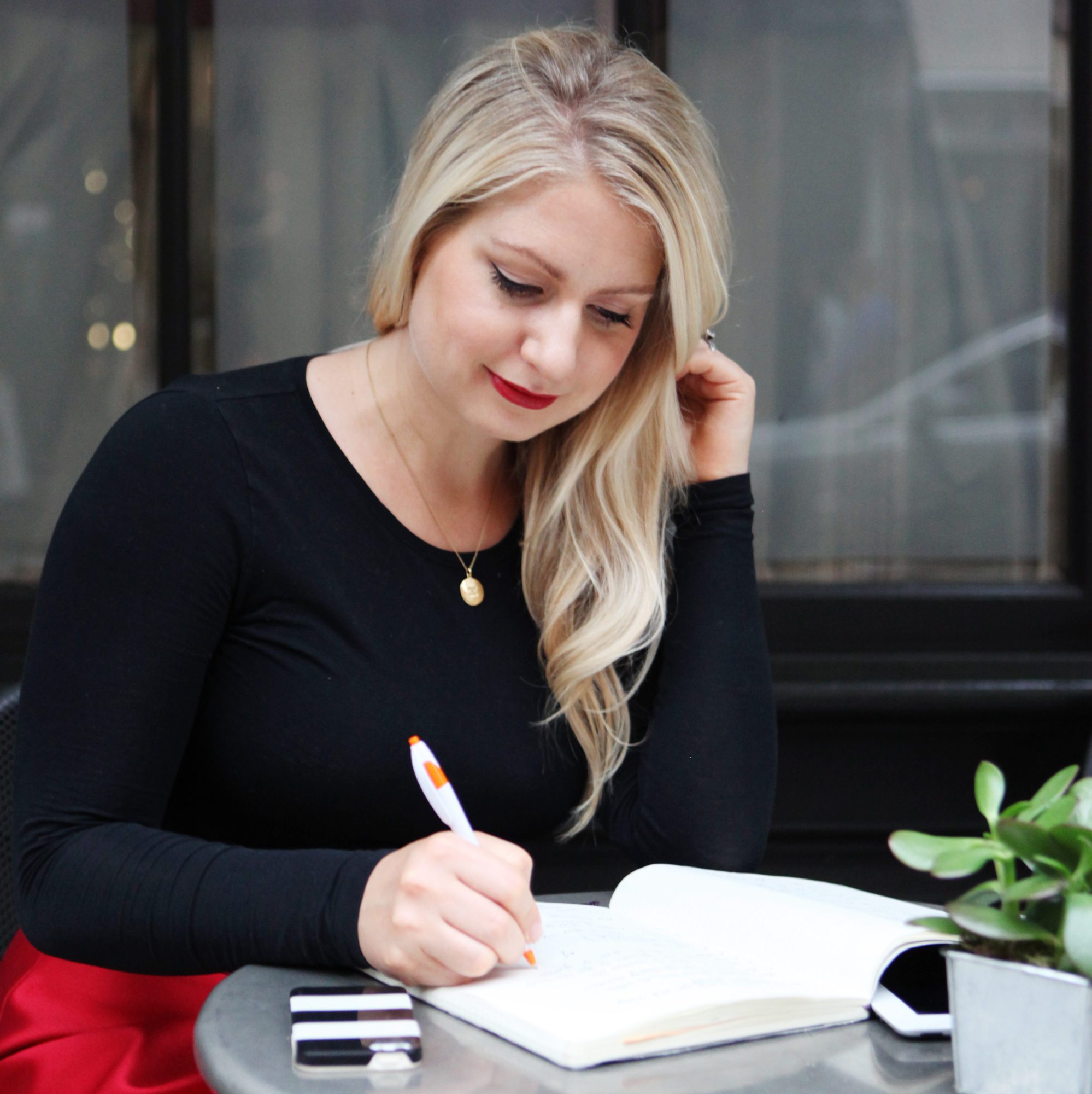 Emily Williams Writing in a Notebook Wearing a Black Sweater