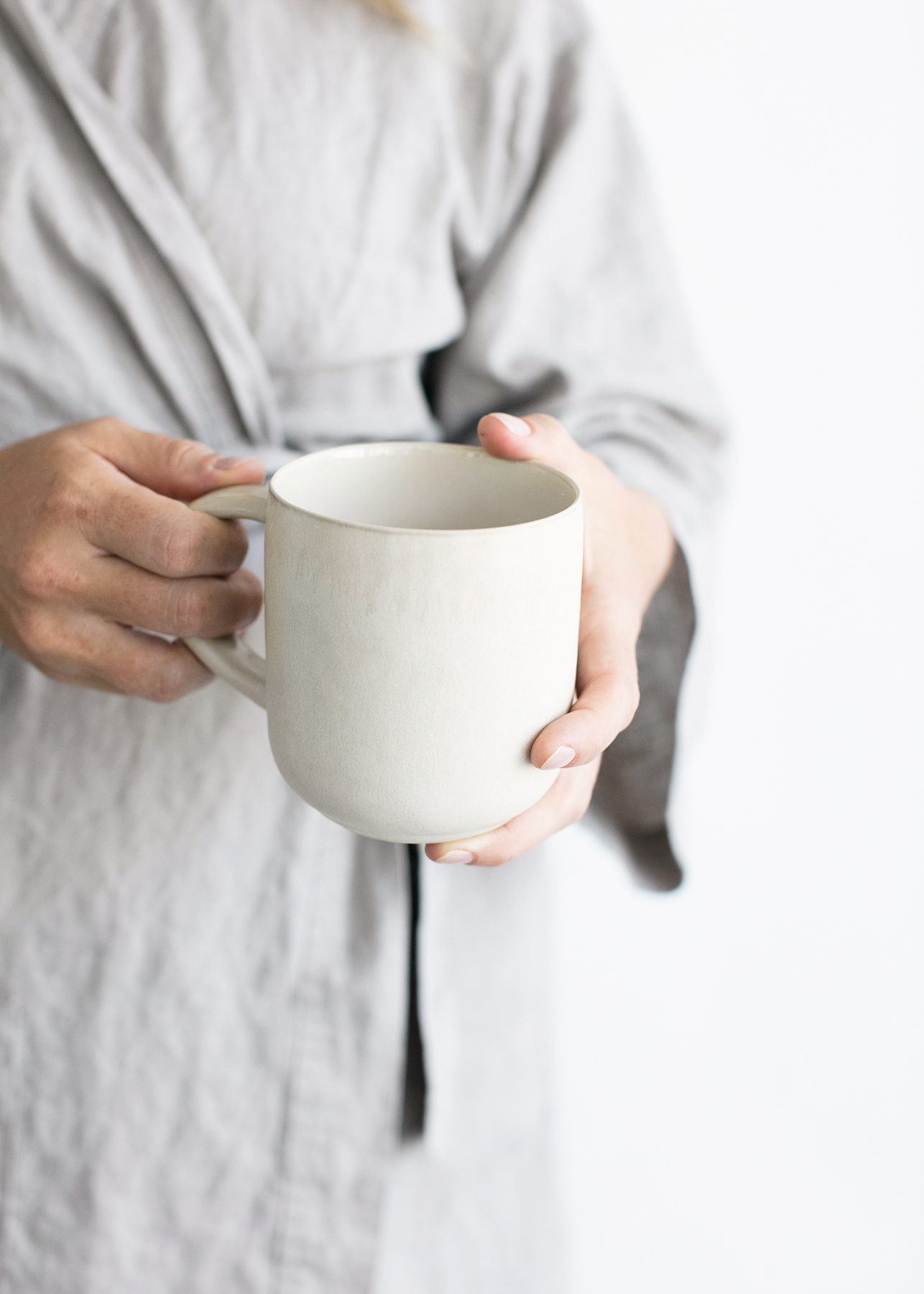 Woman in Grey Robe holding a Beige Ceramic Mug