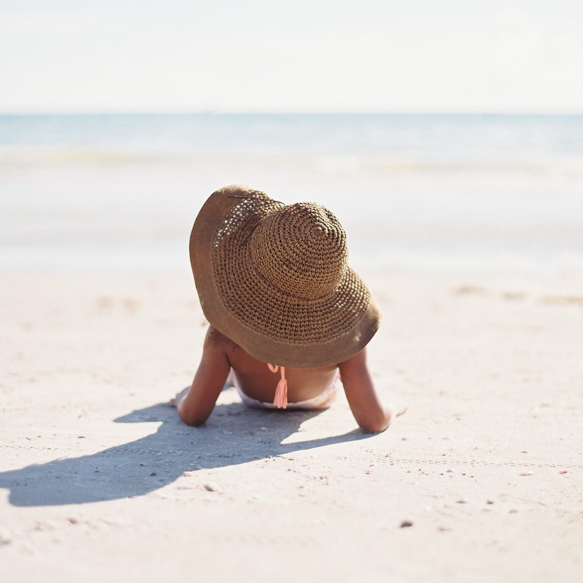 Woman lying on the sand with a big sun hat on