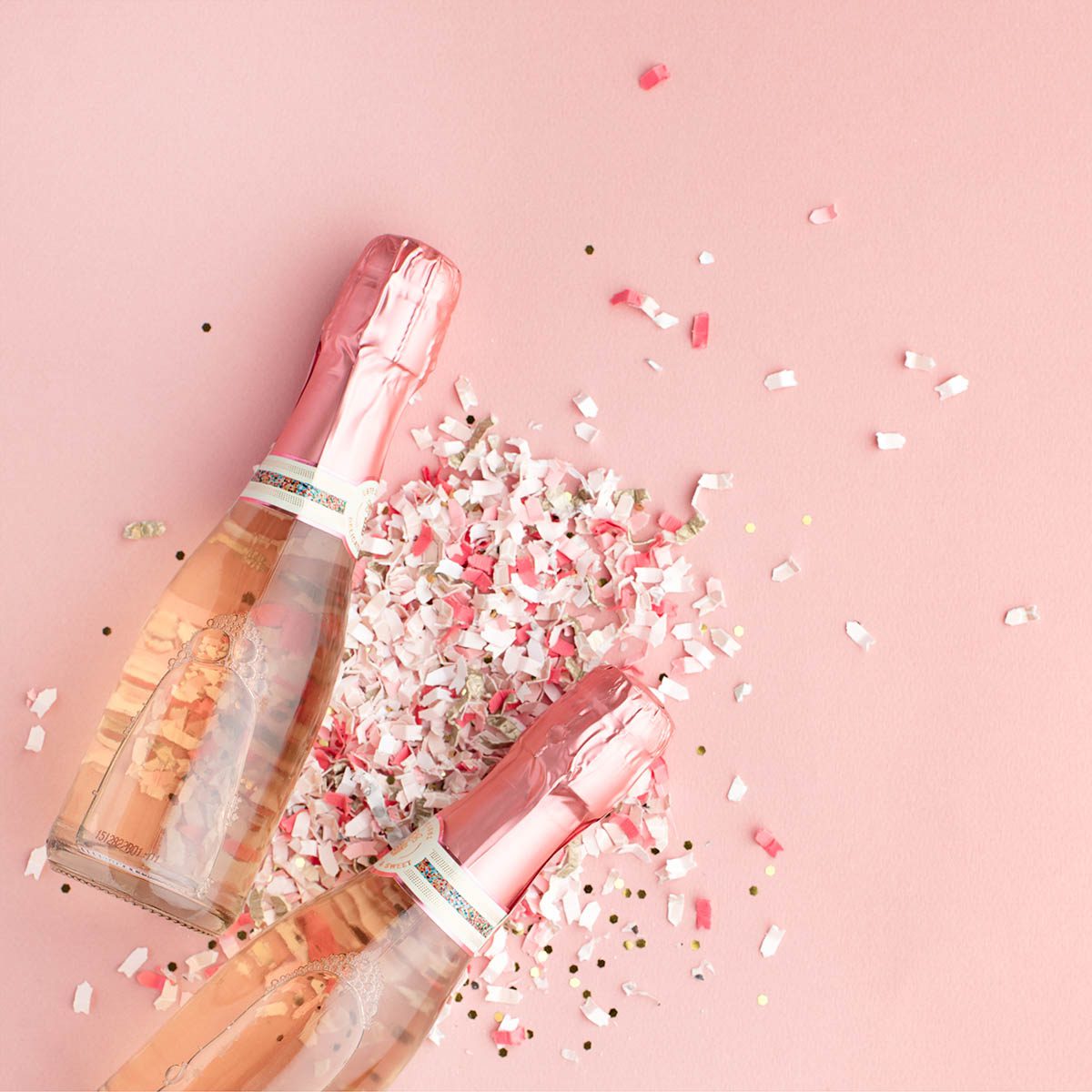 Two mini rose champagne glasses with confetti around them