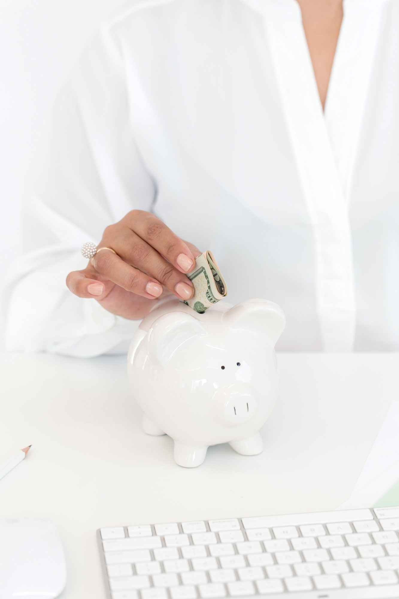 Woman placing money in a white piggy bank
